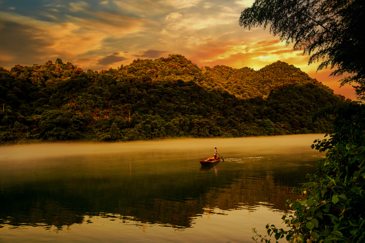 傍晚小东江江面又泛起了浓雾一个渔民泛舟江上霞光映照在江面上画面