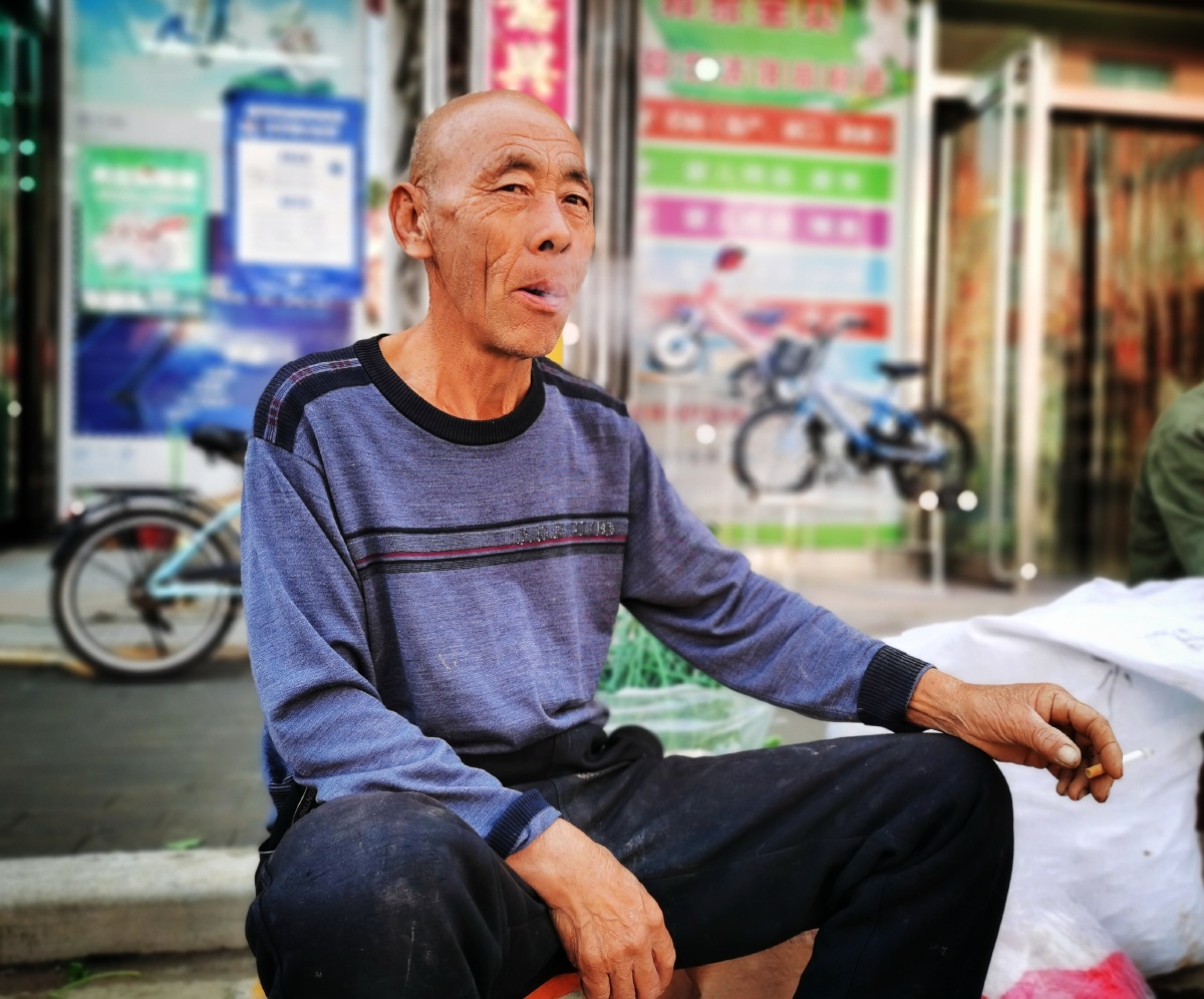 今天早上在周村古镇的集市上拍到了一位卖菜老汉,口里抽着烟,表情或