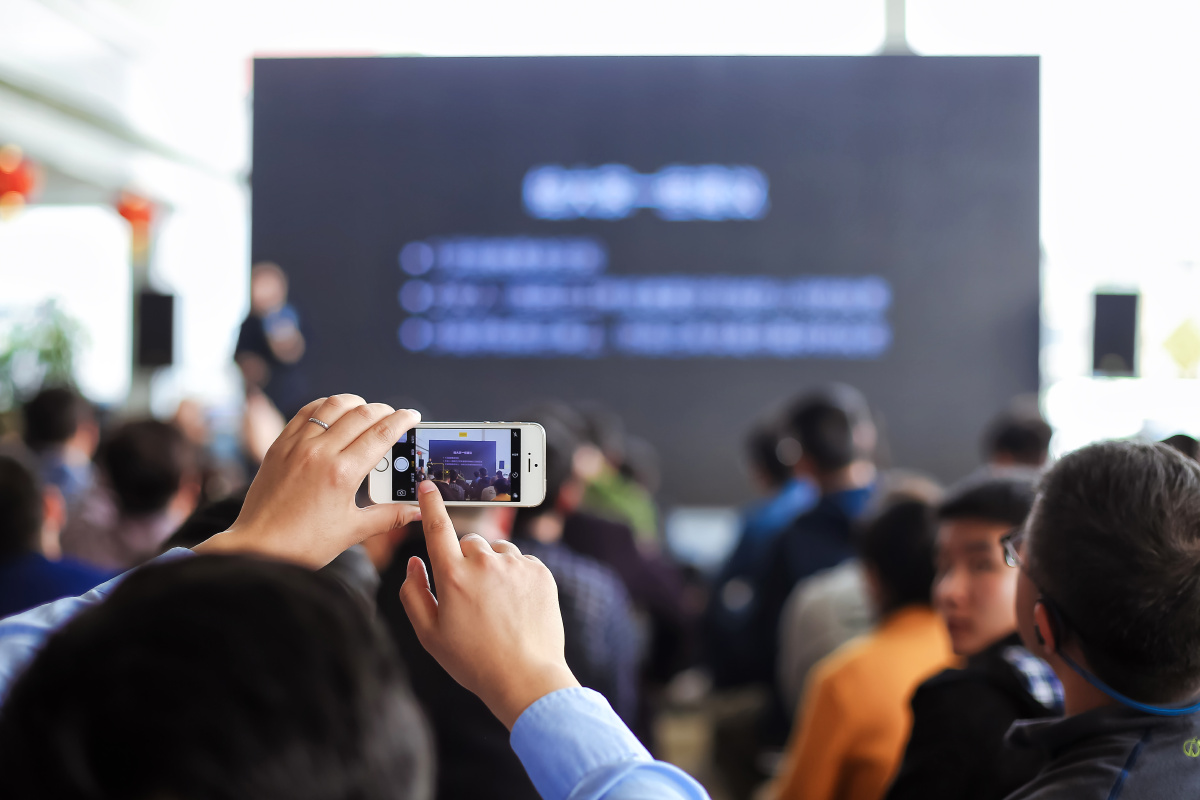 会议沙龙演讲活动现场有人拿着举着苹果手机拍照