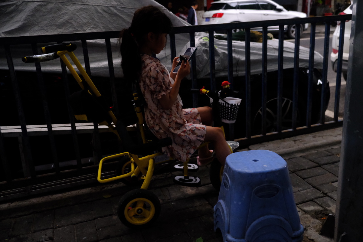 路边玩手机的小女孩