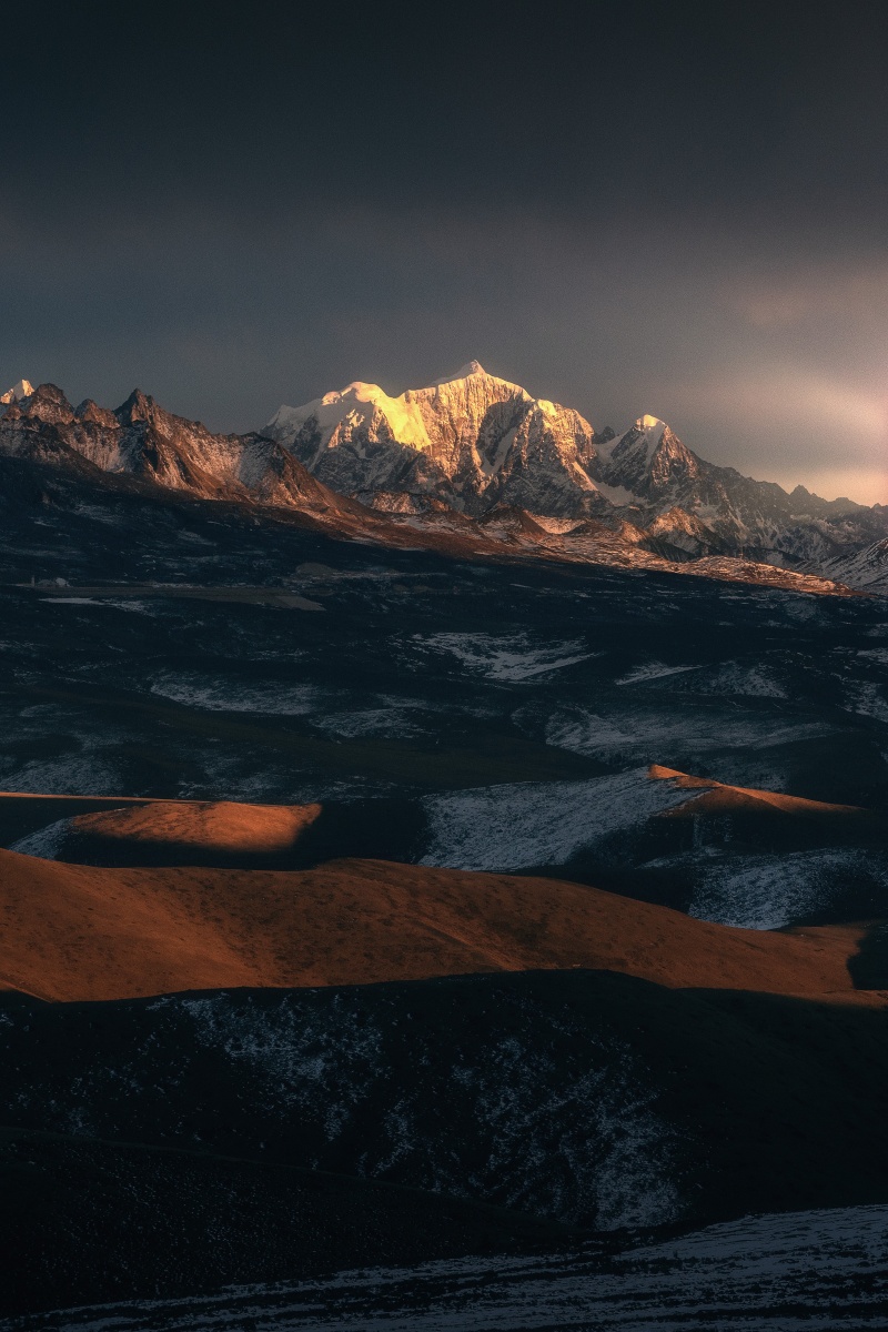 冬季的田海子山在乌云的缝隙中透出的夕阳