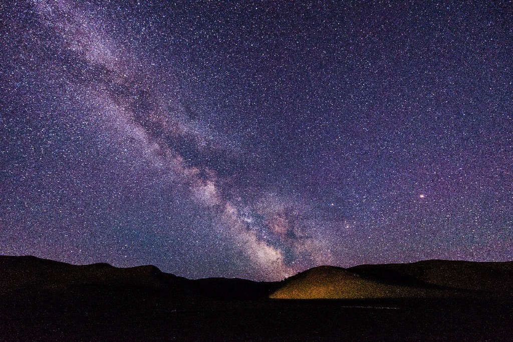 盛夏，草原上的夜晚还带着丝丝寒冷，在没电没网没信号的阿旗草原上，清晰的银河从天边升起，远处打来的一束灯光照亮了小山丘。